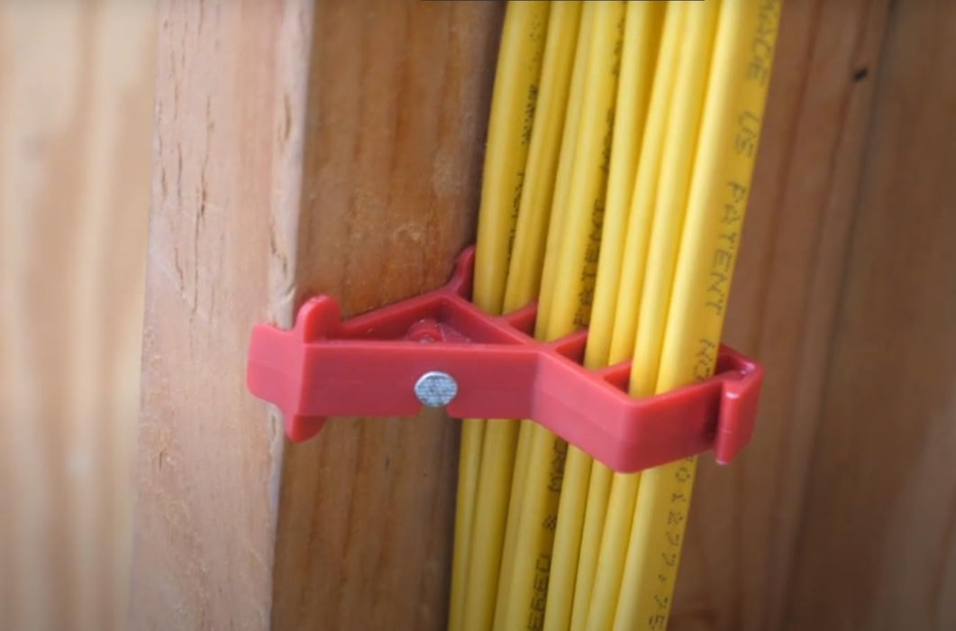 Red Wire Staples holding yellow cable against a wooden wall